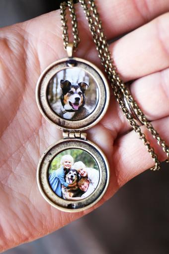 Mano di donna che tiene un medaglione antico con foto di bambini e cane da compagnia all'interno