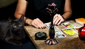 L'indovino dispone le carte dei tarocchi con un gatto nero seduto vicino