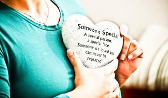 Donna che tiene un tributo di cuore in memoria della persona amata deceduta