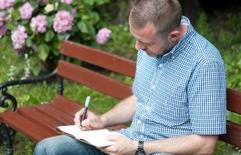 uomo che scrive in un blocco note