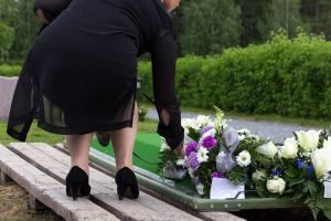 Mostra una donna che depone fiori su una tomba come ricordo