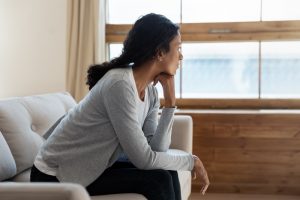 triste donna seduta a casa a guardare fuori dalla finestra