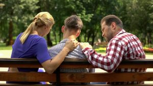 genitori che confortano il figlio adolescente