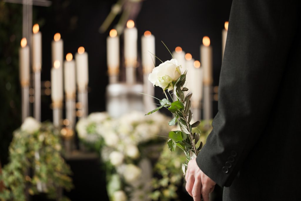 Religione, morte e dolore - uomo al funerale con rosa bianca che piange i morti