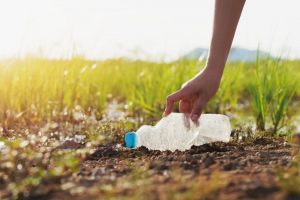 Persona che raccoglie una bottiglia d'acqua vuota