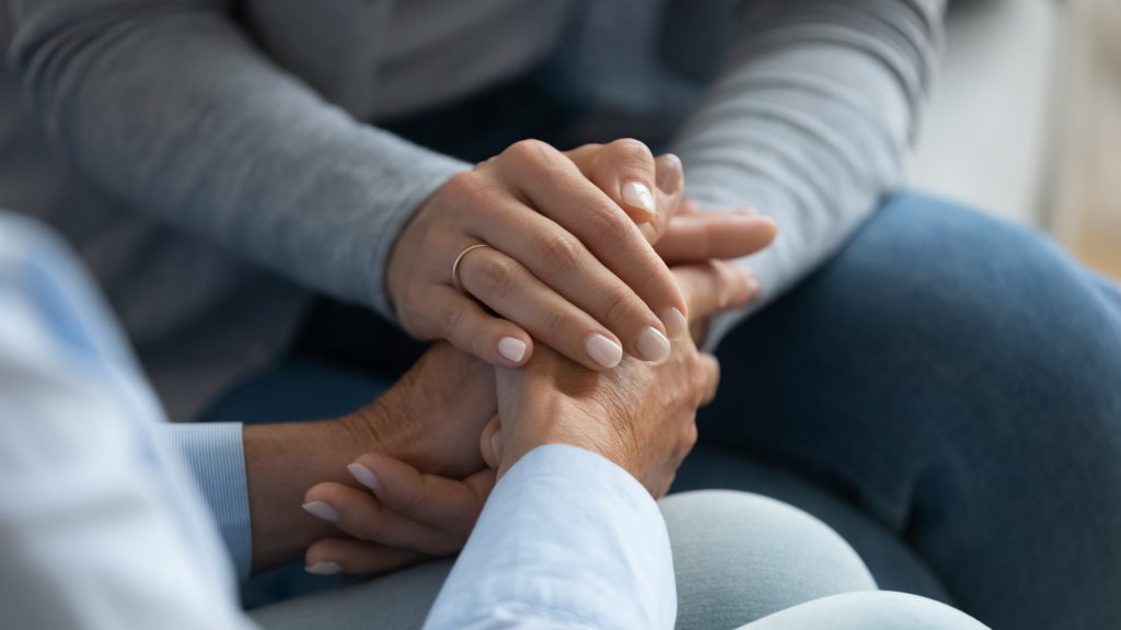Figlia adulta che conforta i colpi di mamma anziana tiene la sua vista ravvicinata della mano.