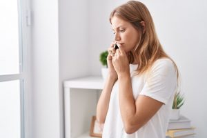 Giovane donna che fa telefonate da casa sua