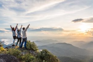 Tre amici festeggiano mentre scalano una montagna dopo un'escursione insieme