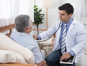 Sindrome del cuore spezzato - uomo anziano in visita con il suo medico, che sta ascoltando il cuore del suo paziente con uno stetoscopio
