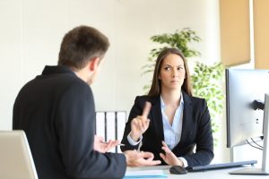 Donna professionale antipatica seduta alla scrivania di fronte al cliente con uno sguardo sconvolto sul viso e alzando severamente il dito indice